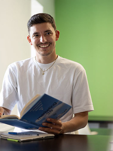 A man smiling and reading a marketing book