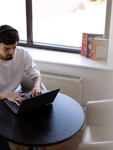 A man with headphones on working at a laptop